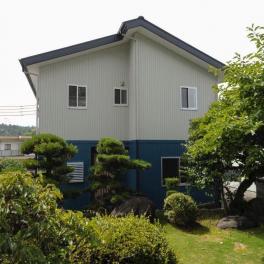 山際に佇む青と白のツートンカラーが印象的な家
